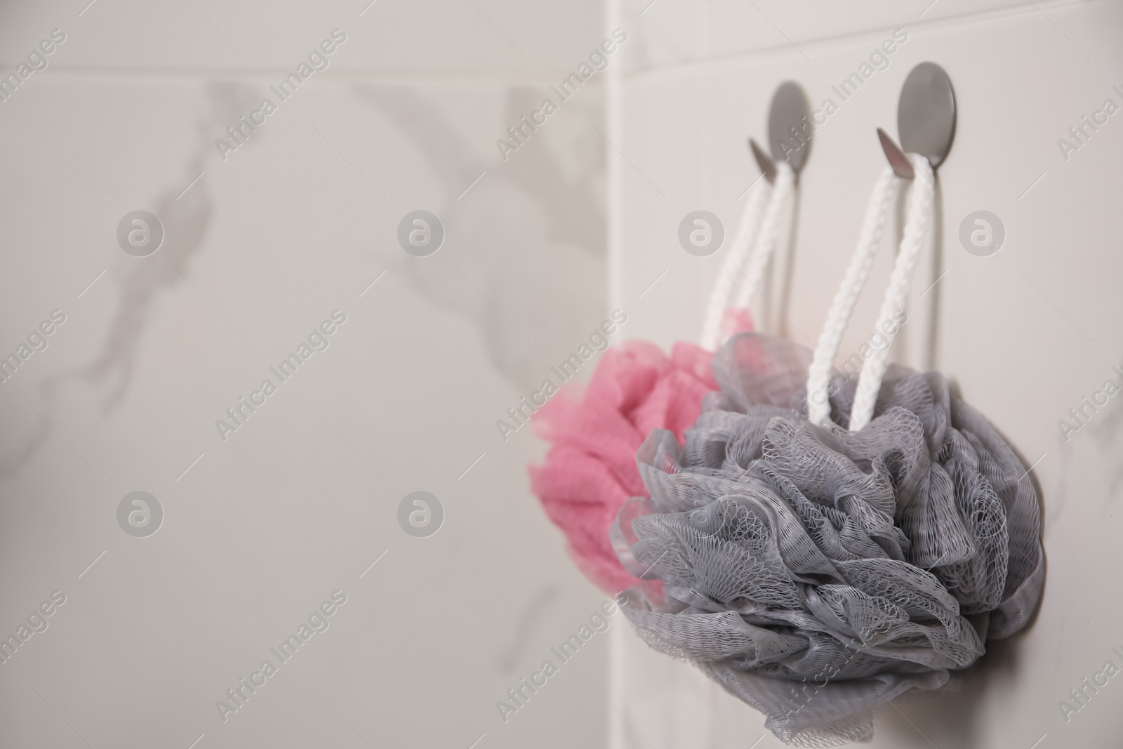 Photo of Shower puffs hanging near faucet in bathroom, space for text