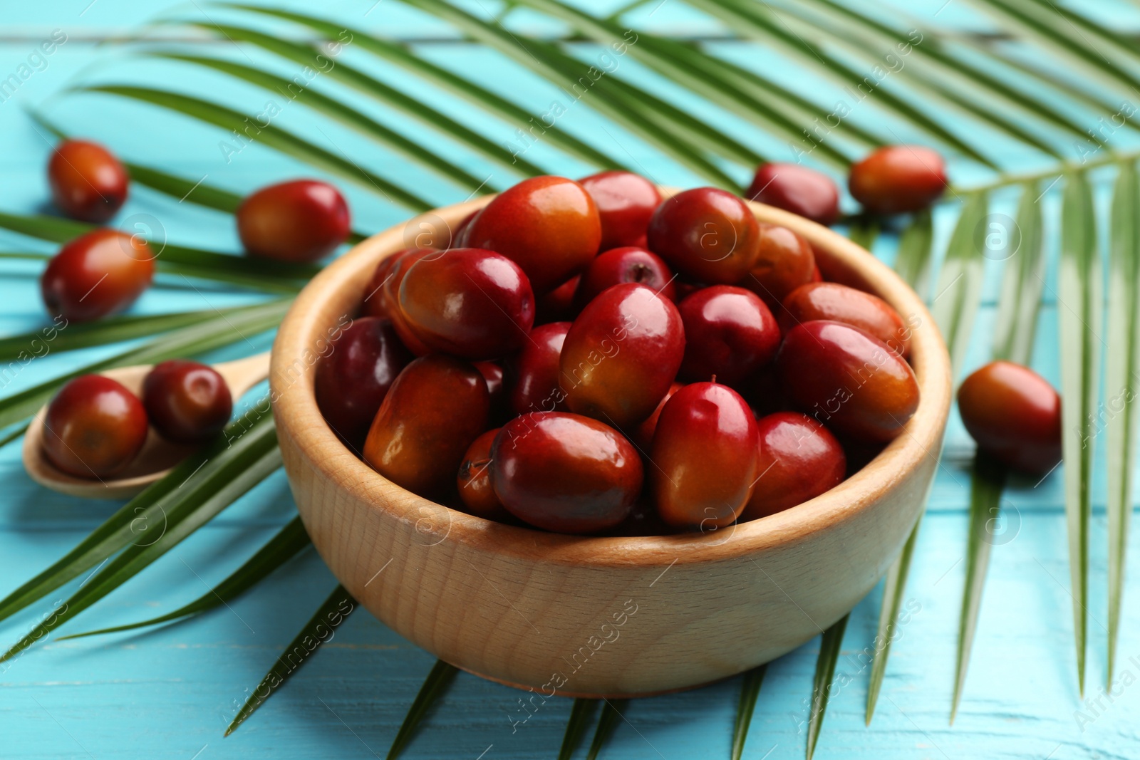 Photo of Palm oil fruits in bowl on turquoise wooden table, closeup