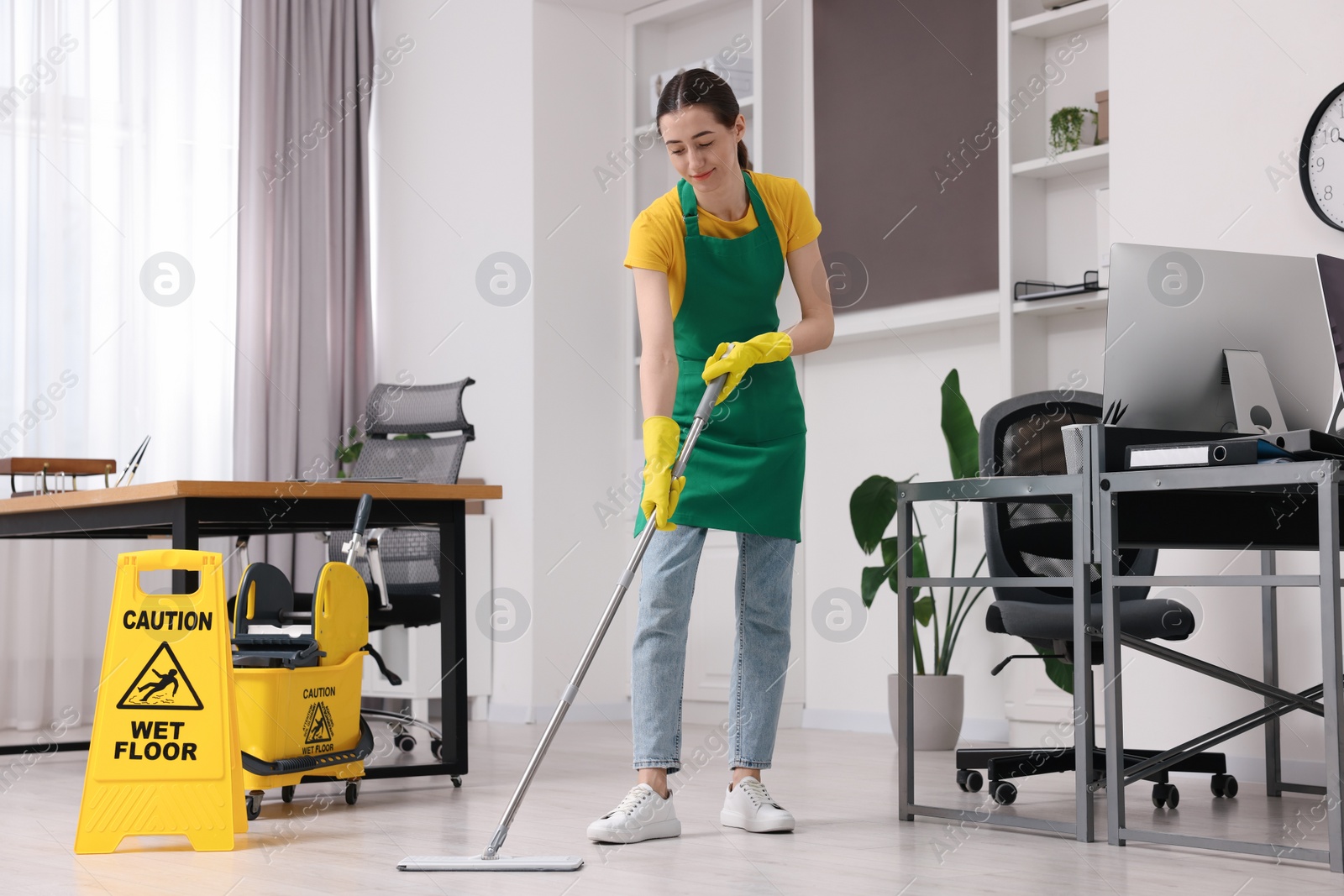 Photo of Cleaning service. Woman washing floor with mop in office