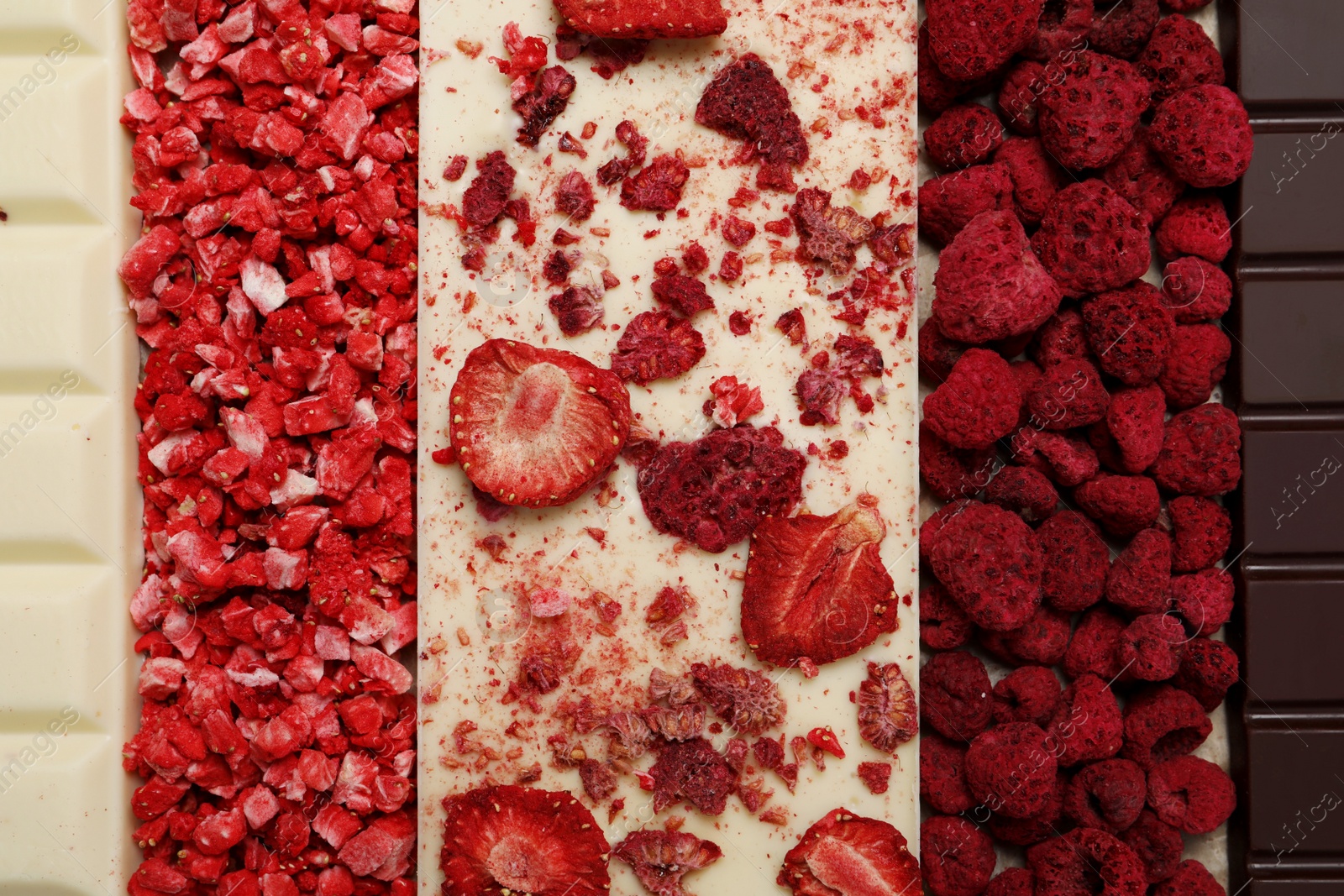 Photo of Chocolate bar with different freeze dried fruits as background, top view