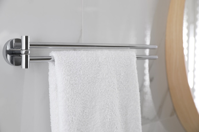 Photo of Holder with clean towel on light wall in bathroom