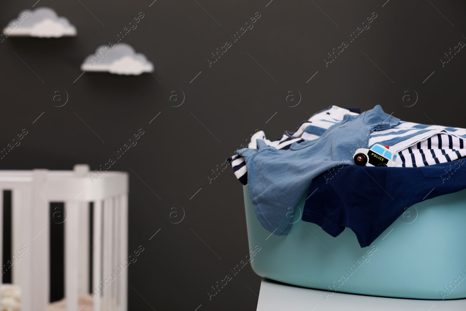 Photo of Laundry basket with baby clothes on white wooden table in child room, space for text