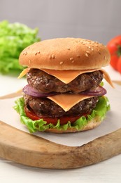 Tasty hamburger with patties, cheese and vegetables on table