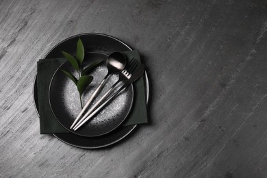 Elegant table setting. Plates, cutlery, napkin and branch with green leaves, flat lay. Space for text