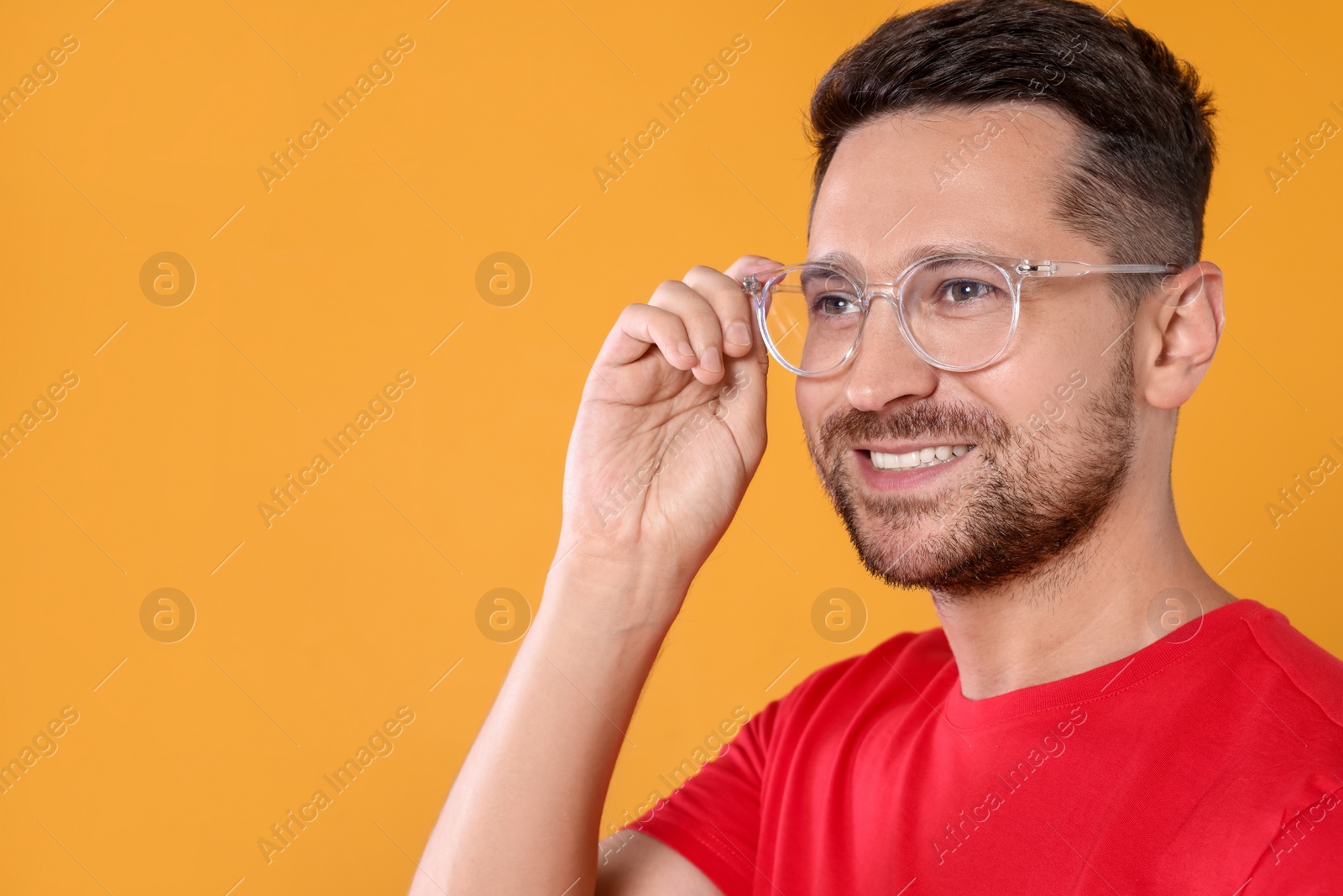 Photo of Portrait of happy man in stylish glasses on yellow background. Space for text