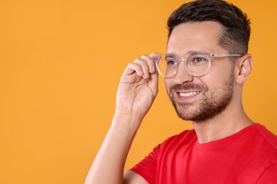 Photo of Portrait of happy man in stylish glasses on yellow background. Space for text