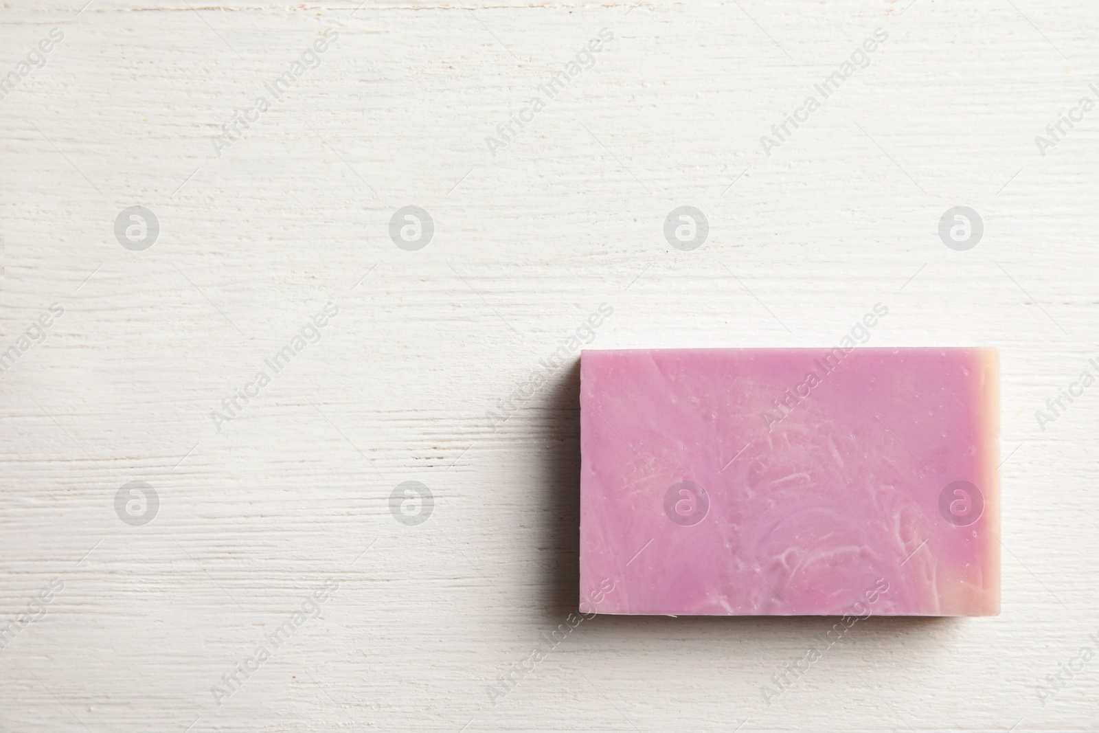 Photo of Hand made soap bar on white wooden background, top view. Space for text