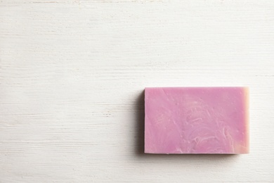 Hand made soap bar on white wooden background, top view. Space for text