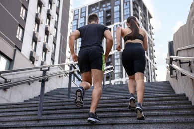 Healthy lifestyle. Couple running up steps outdoors, low angle view