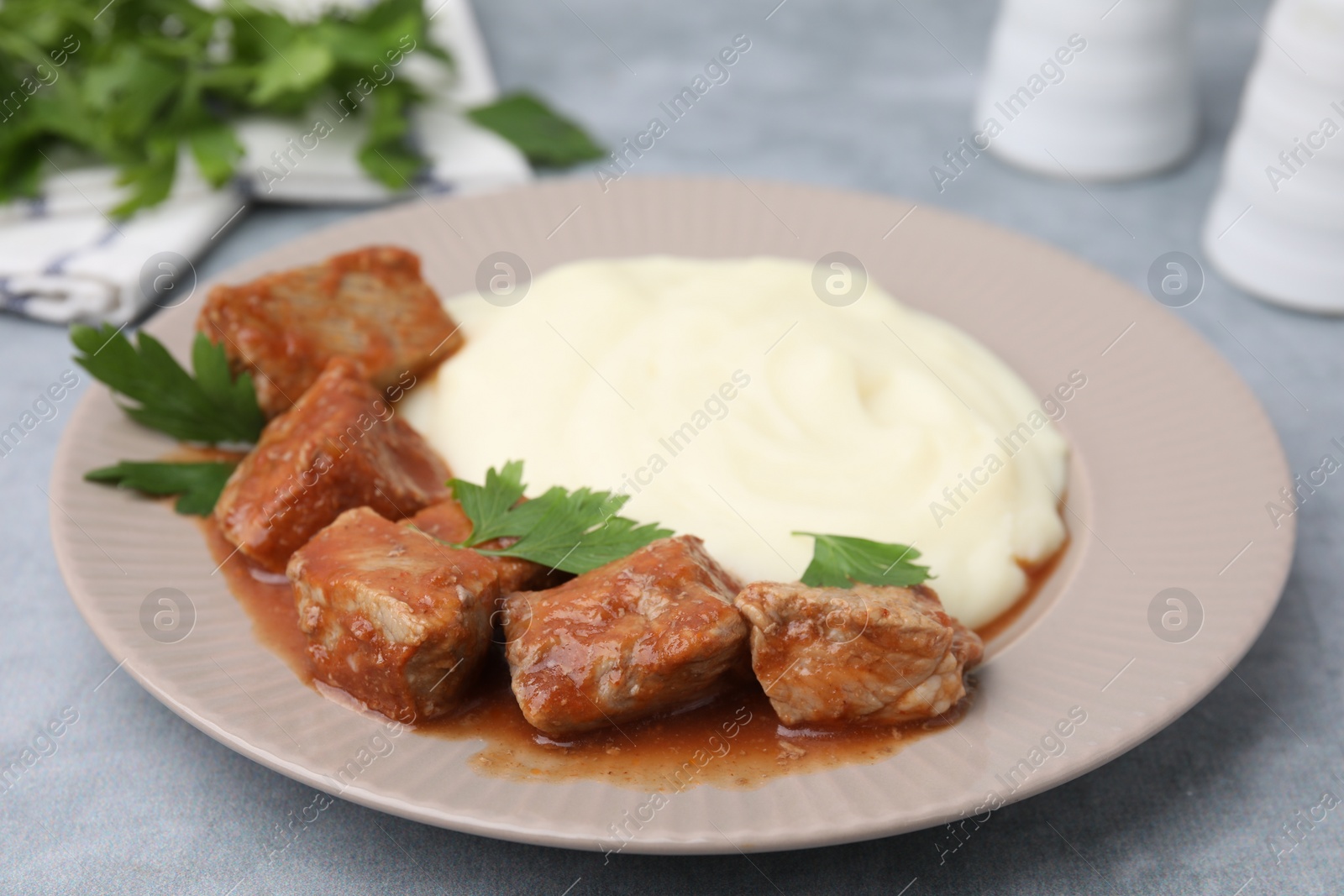 Photo of Delicious goulash served with mashed potato on light grey table, closeup