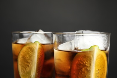 Photo of Glasses of refreshing soda drinks with ice cubes and lime on grey background, closeup. Space for text