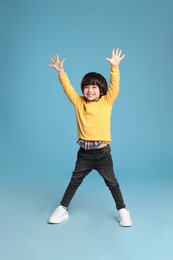 Full length portrait of cute little boy on light blue background