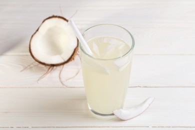 Photo of Glass of coconut water and nut on white wooden table