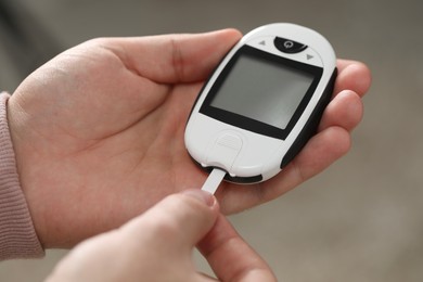 Diabetes test. Man with glucometer on blurred background, closeup