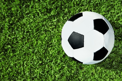 Photo of Soccer ball on fresh green football field grass, top view. Space for text
