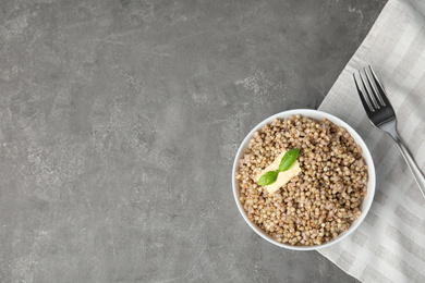 Photo of Tasty buckwheat porridge with butter on grey table, flat lay. Space for text