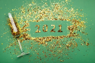 Photo of Flat lay composition with confetti and champagne glass on green background. New Year celebration