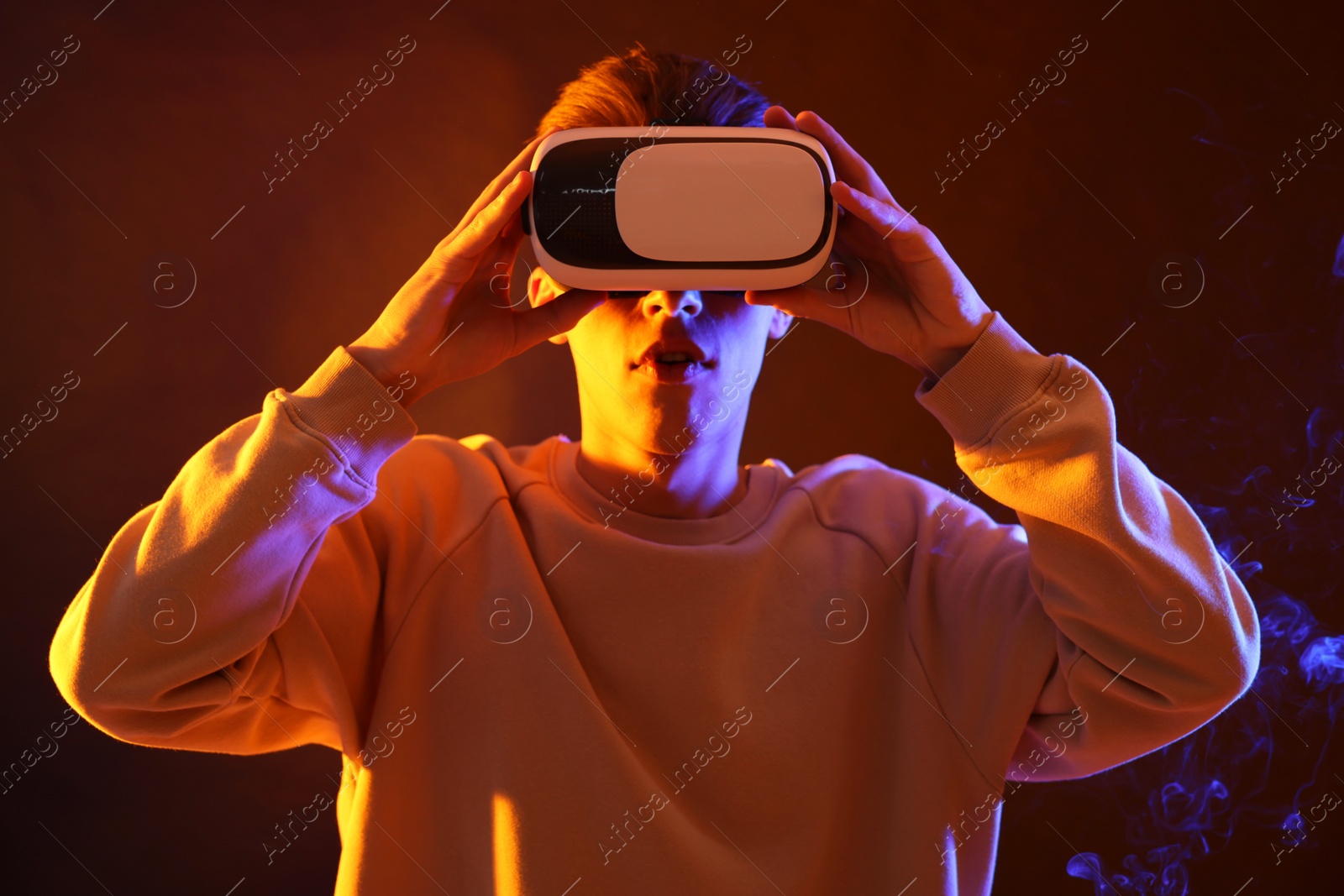 Photo of Young man with virtual reality headset on brown background