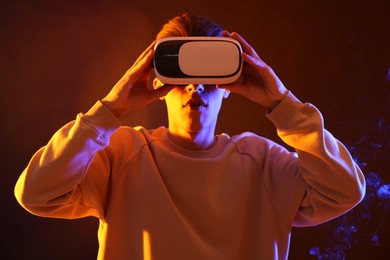 Young man with virtual reality headset on brown background