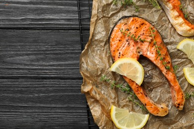 Tasty grilled salmon steak and ingredients on black wooden table, top view. Space for text