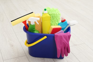 Different cleaning supplies in bucket on floor