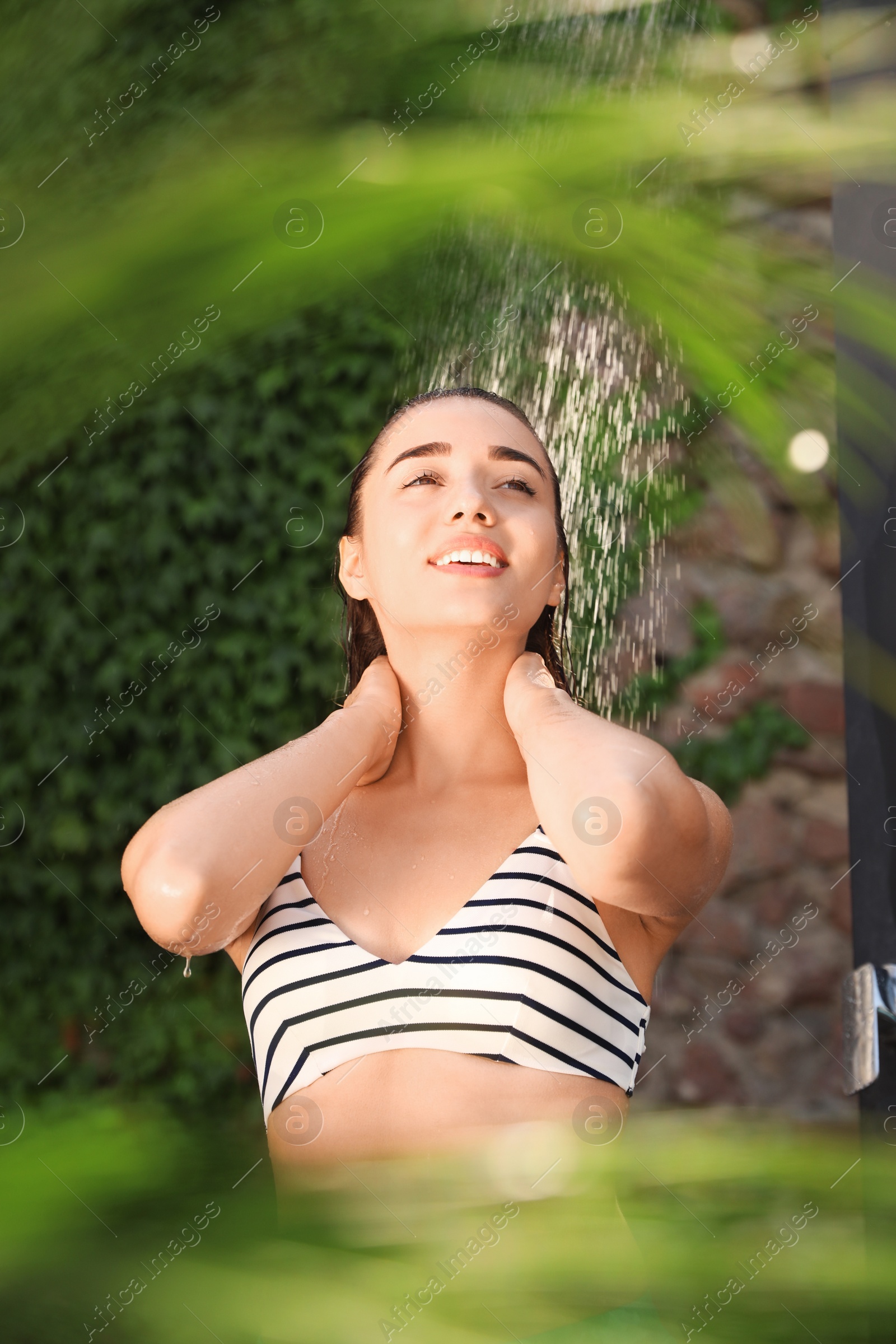 Photo of Woman washing hair in outdoor shower on summer day