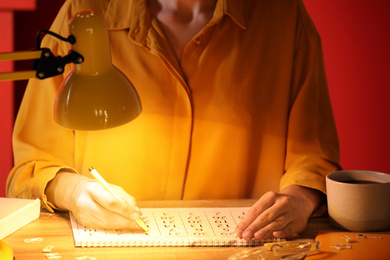 Photo of Woman marking date in calendar at wooden table, closeup