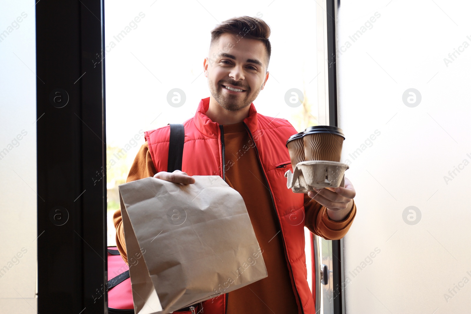 Photo of Portrait of courier with order at open door. Food delivery service