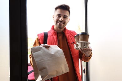 Portrait of courier with order at open door. Food delivery service