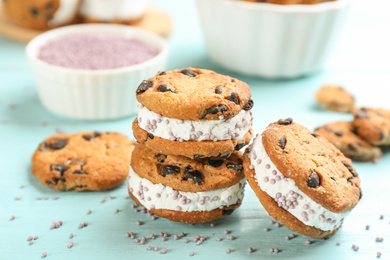 Photo of Sweet delicious ice cream cookie sandwiches on light blue wooden table, closeup