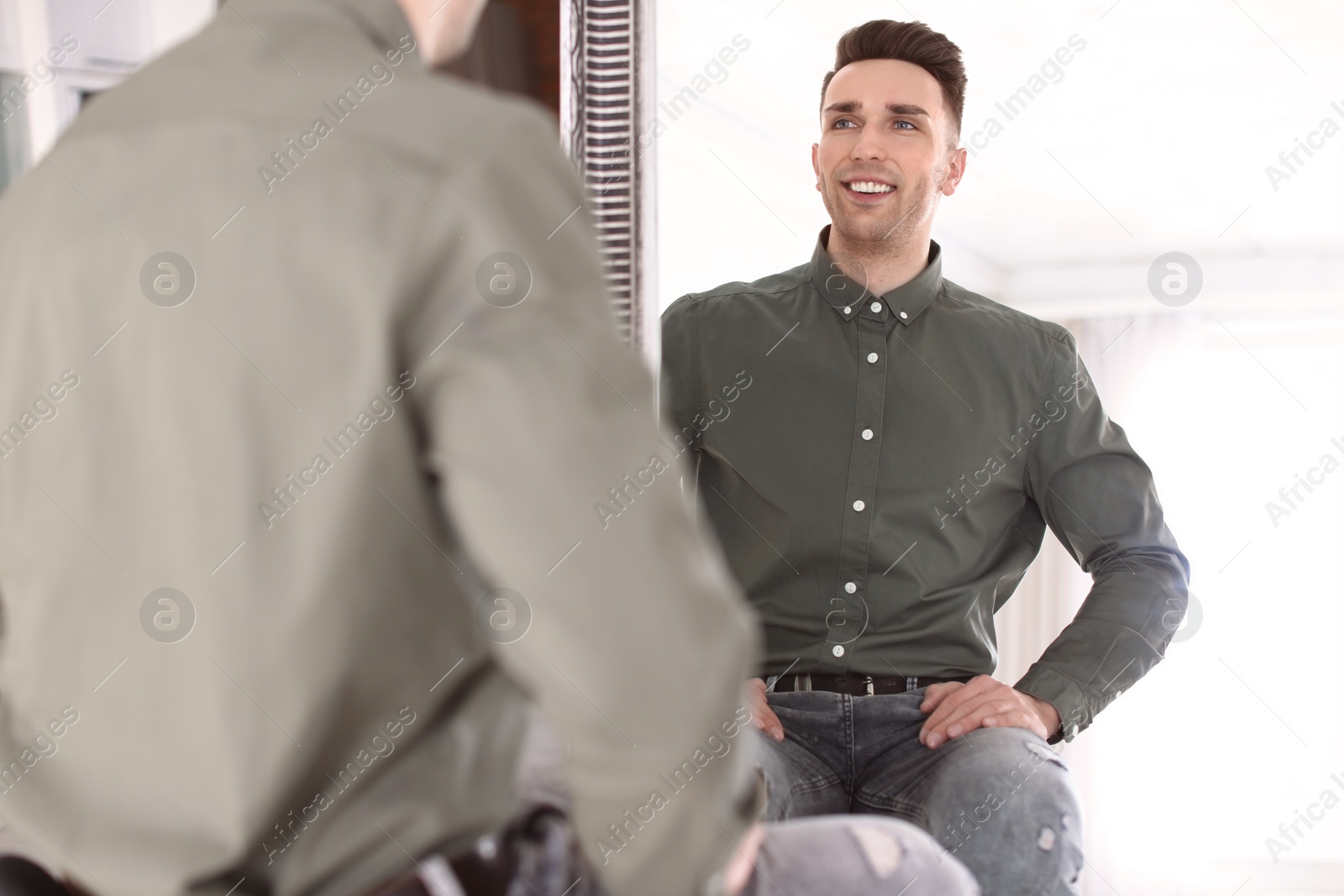 Photo of Young man looking in mirror at home