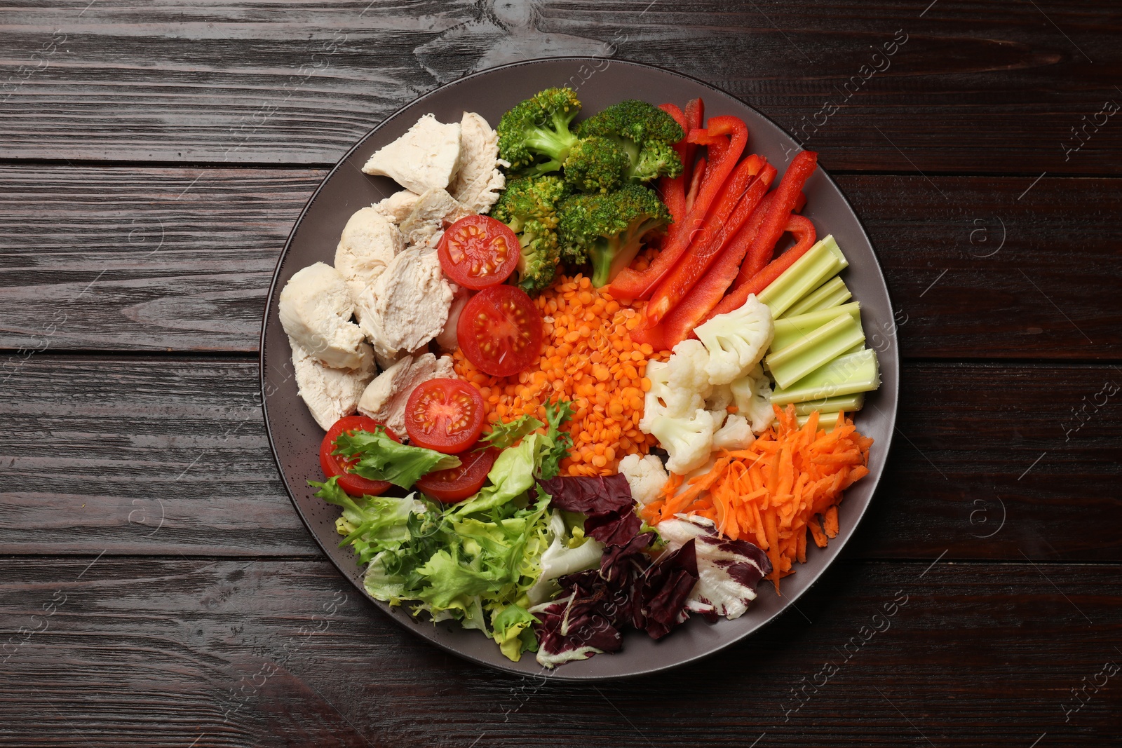 Photo of Balanced diet and healthy foods. Plate with different delicious products on dark wooden table, top view