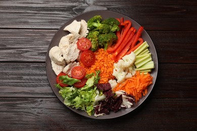 Balanced diet and healthy foods. Plate with different delicious products on dark wooden table, top view