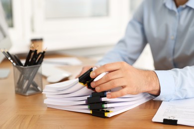 Photo of Man working with documents at wooden table in office, closeup