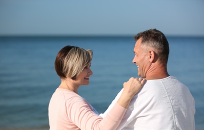 Happy mature couple together at beach on sunny day