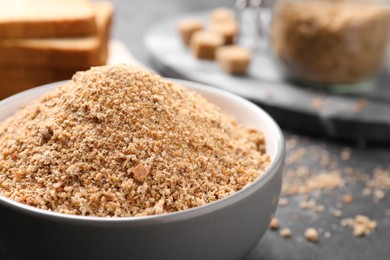 Photo of Fresh breadcrumbs in bowl on black table, closeup