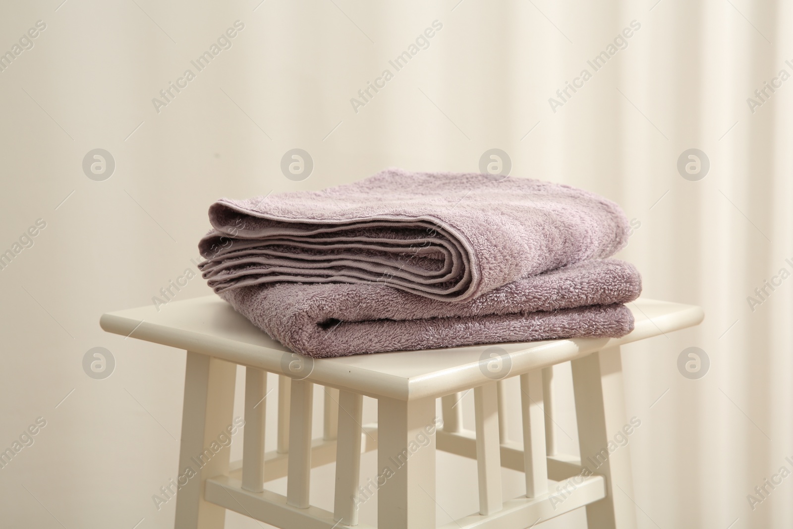 Photo of Violet towels on stool against white wall