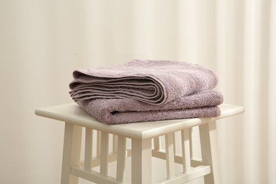 Violet towels on stool against white wall