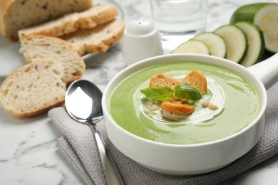 Photo of Tasty homemade zucchini cream soup served on marble table