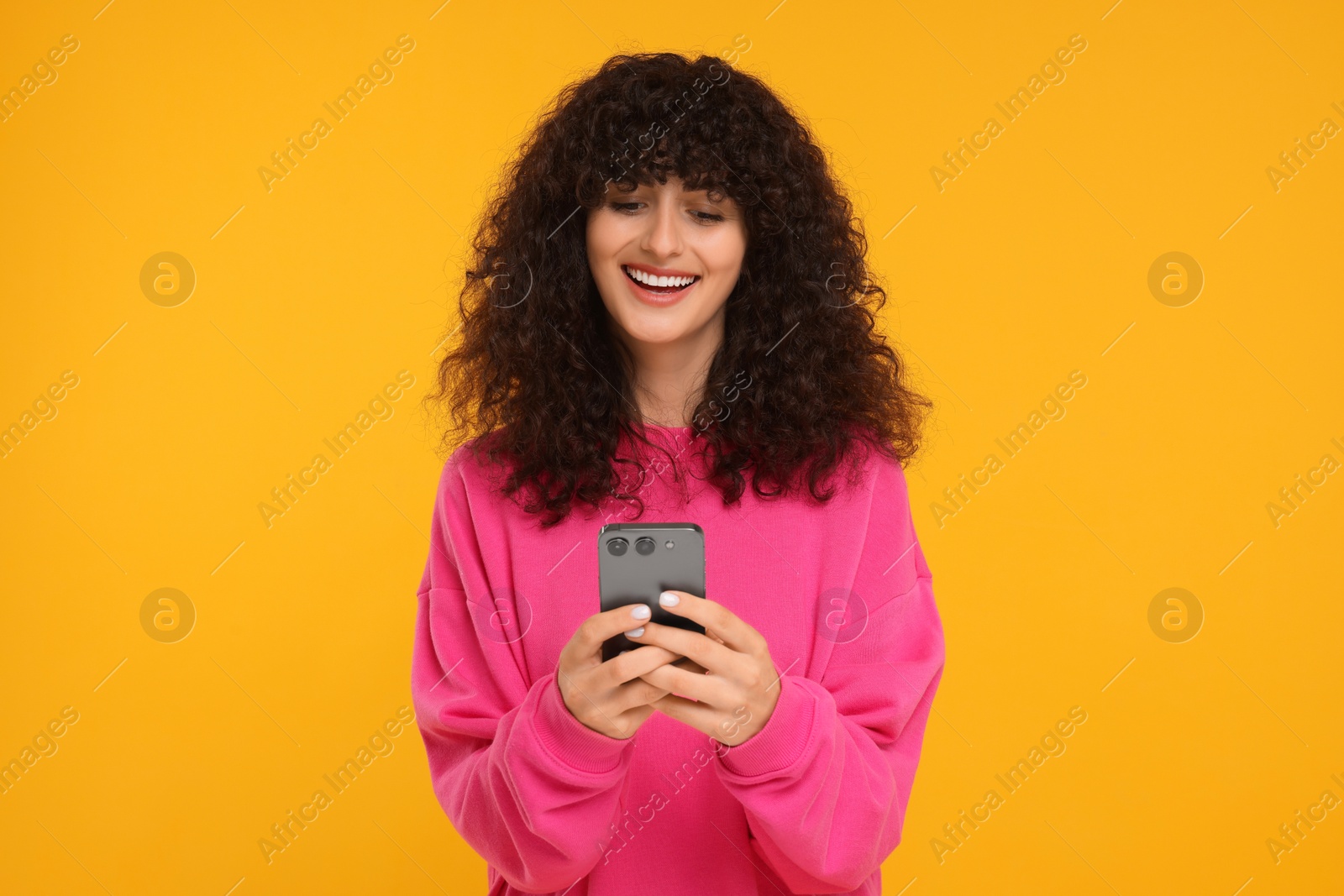 Photo of Happy young woman using smartphone on yellow background