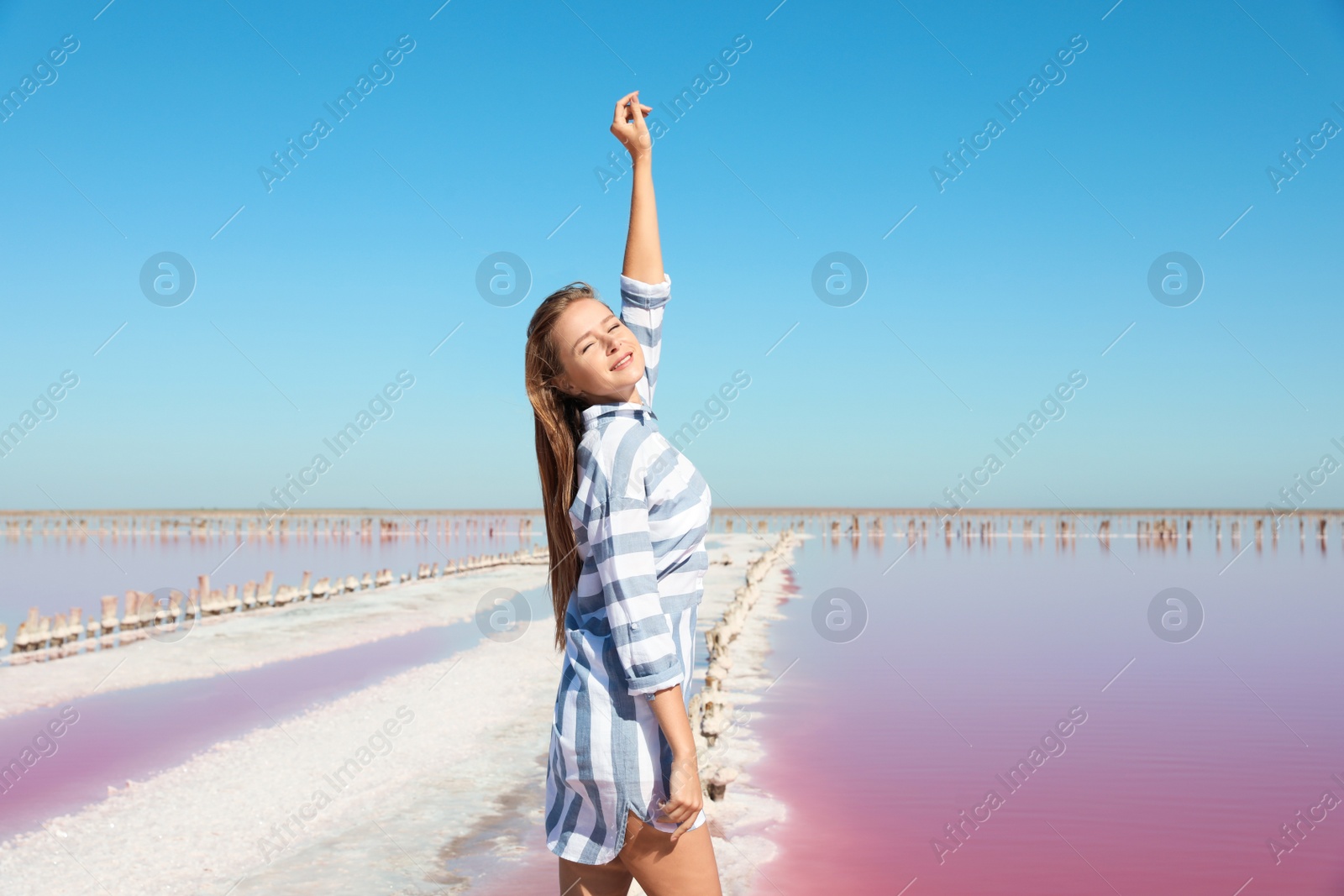 Photo of Beautiful woman posing near pink lake on summer day