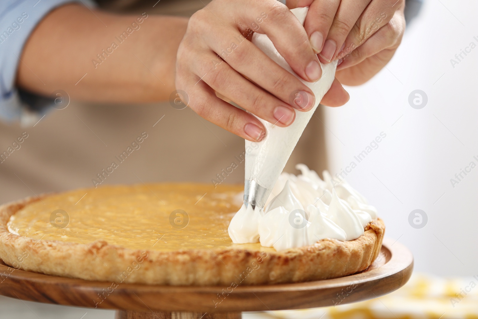 Photo of Woman preparing lemon meringue pie in kitchen, closeup of hands