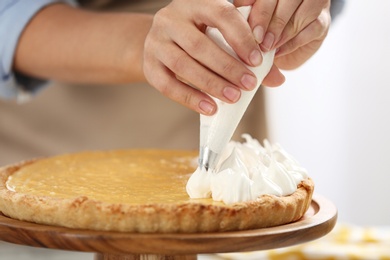 Woman preparing lemon meringue pie in kitchen, closeup of hands