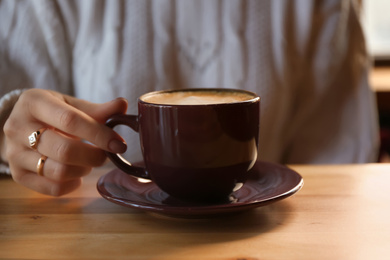 Photo of Woman with aromatic coffee at table in cafe, closeup