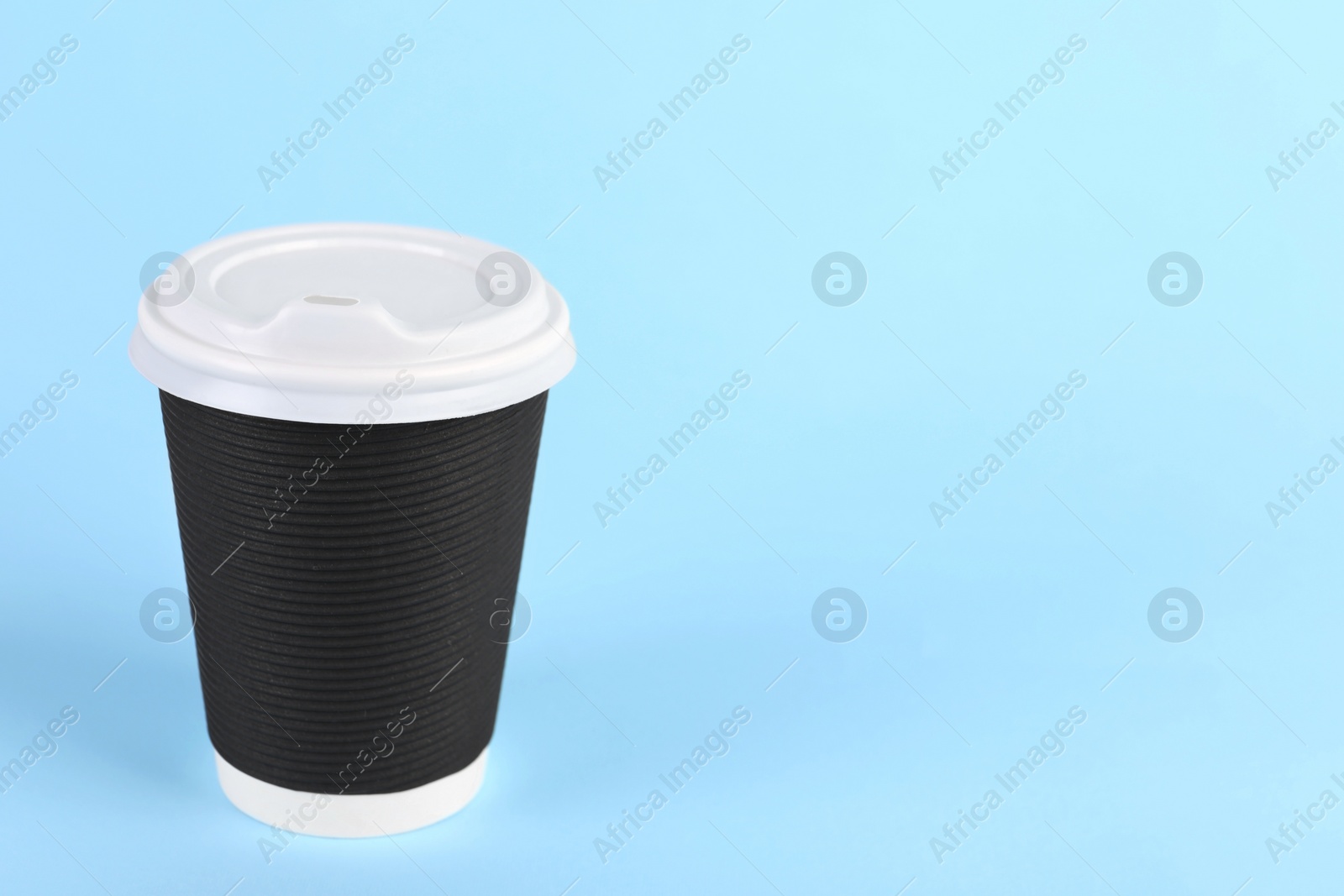 Photo of Black paper cup with plastic lid on light blue background, space for text. Coffee to go