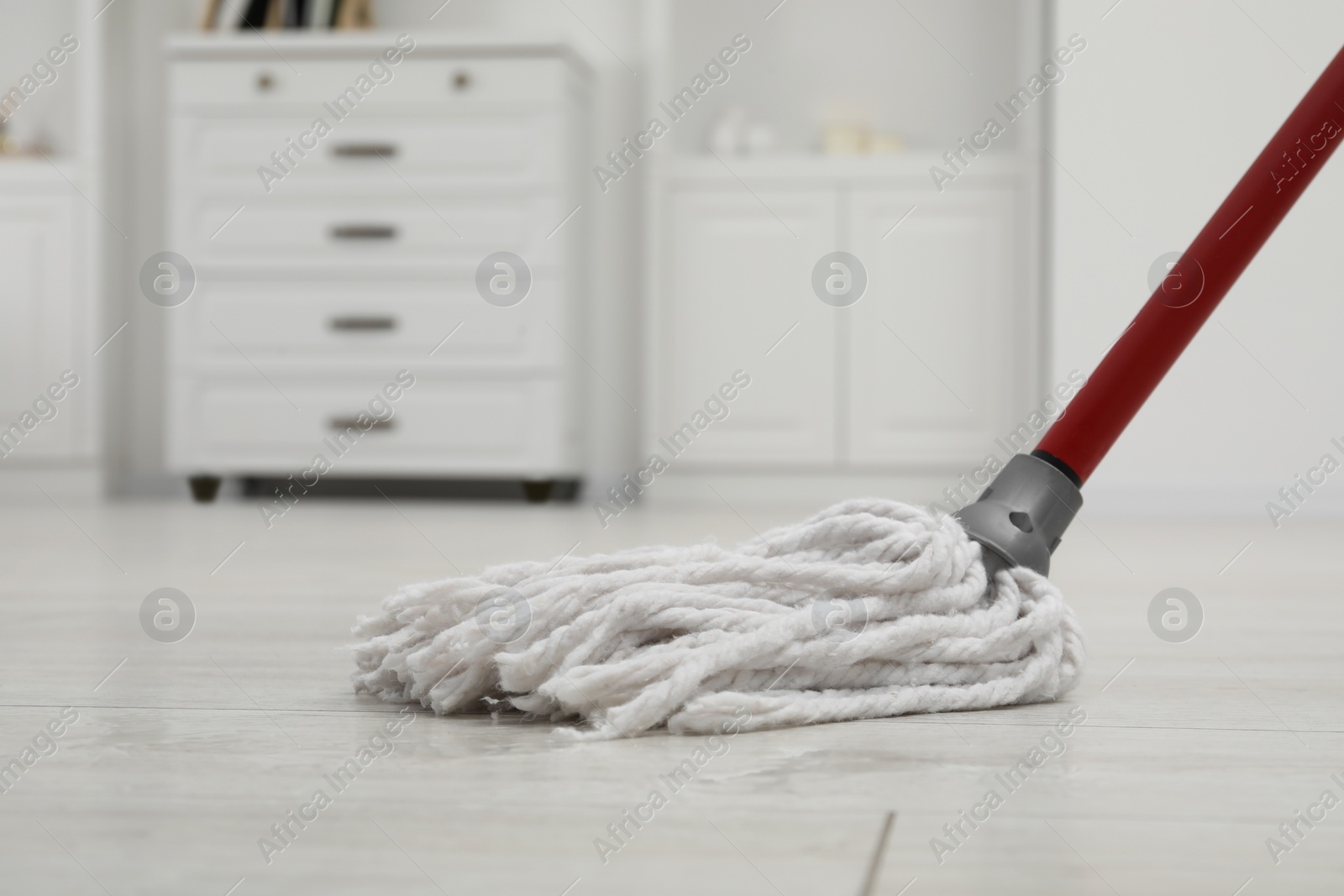 Photo of Cleaning white parquet floor with mop indoors, closeup