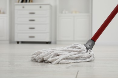 Cleaning white parquet floor with mop indoors, closeup