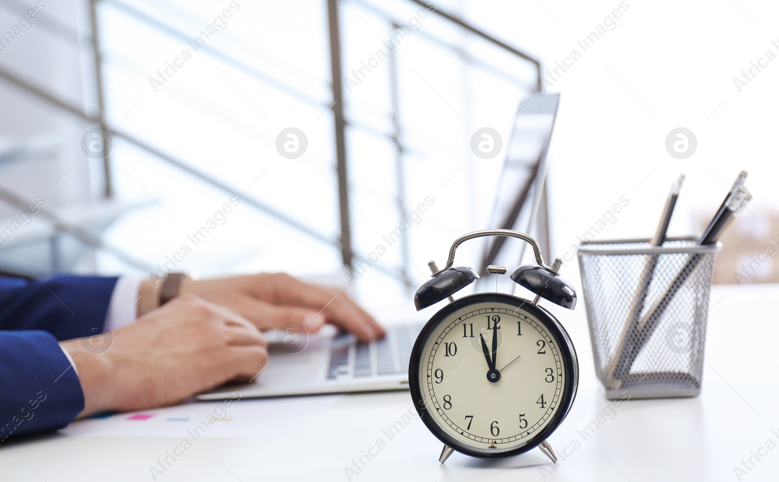 Photo of Clock and blurred man working on background. Time management