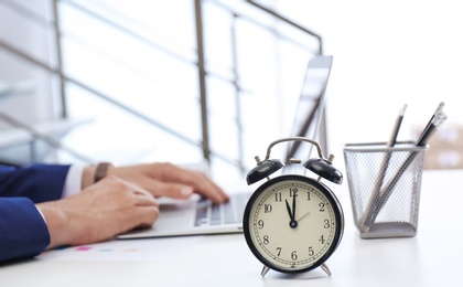 Photo of Clock and blurred man working on background. Time management