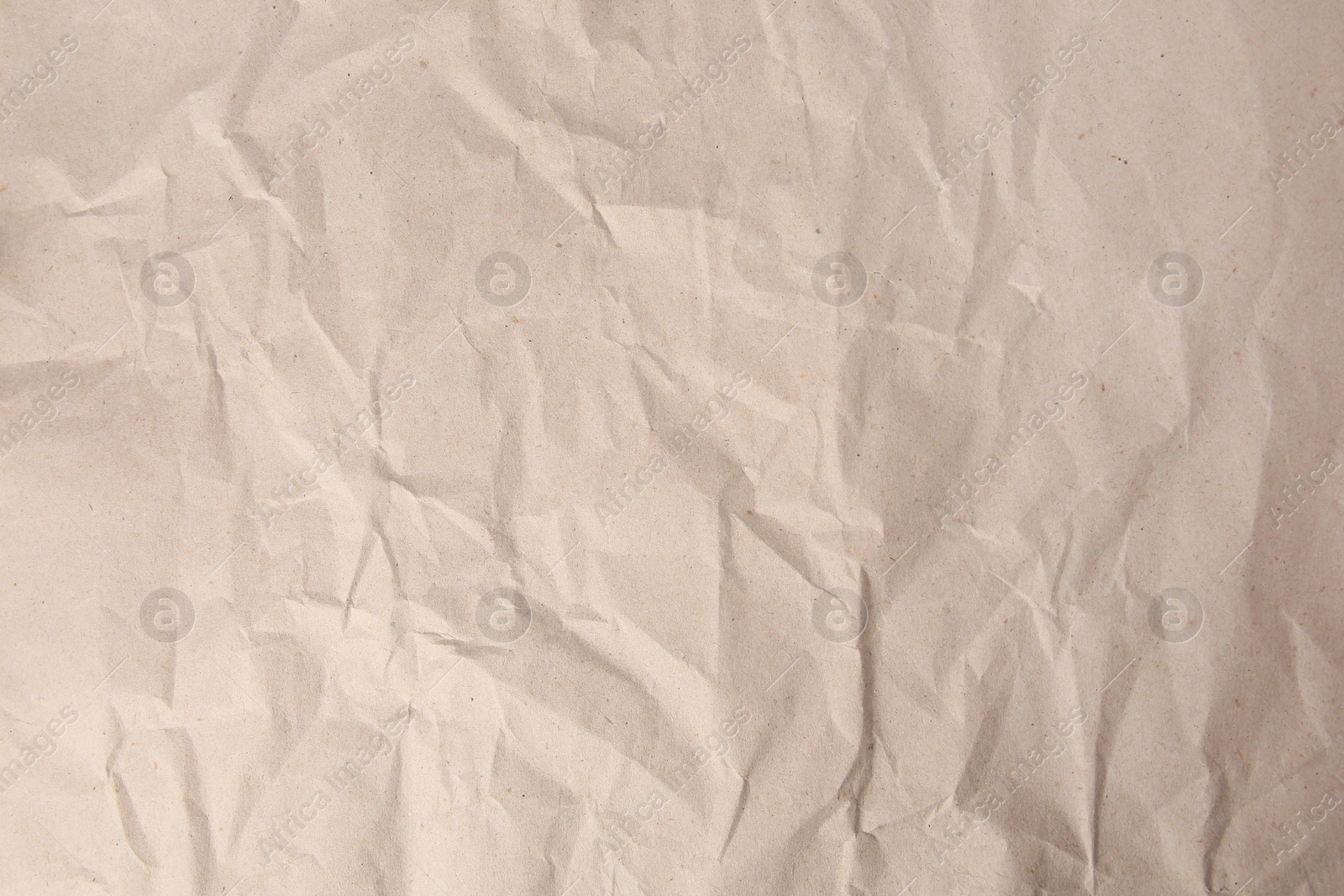 Photo of Sheet of crumpled light brown paper as background, top view